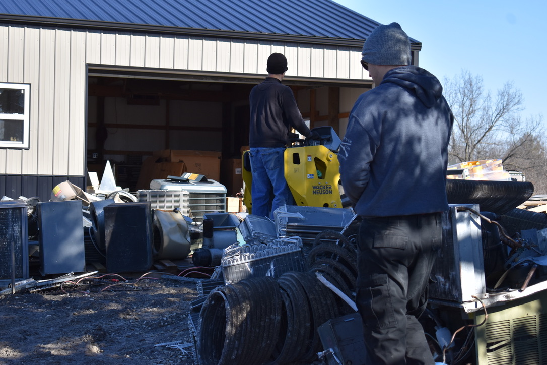Worker loading HVAC scraps into a dump trailer in Troy, MO, professional junk removal and hauling service
