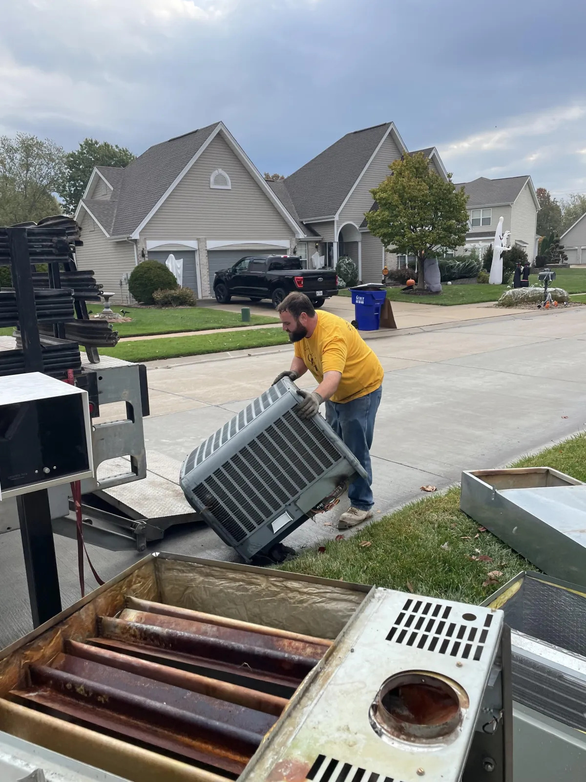 Goldkamp technician removing old outdoor AC condenser for junk removal and HVAC replacement in a residential neighborhood in Troy, MO.